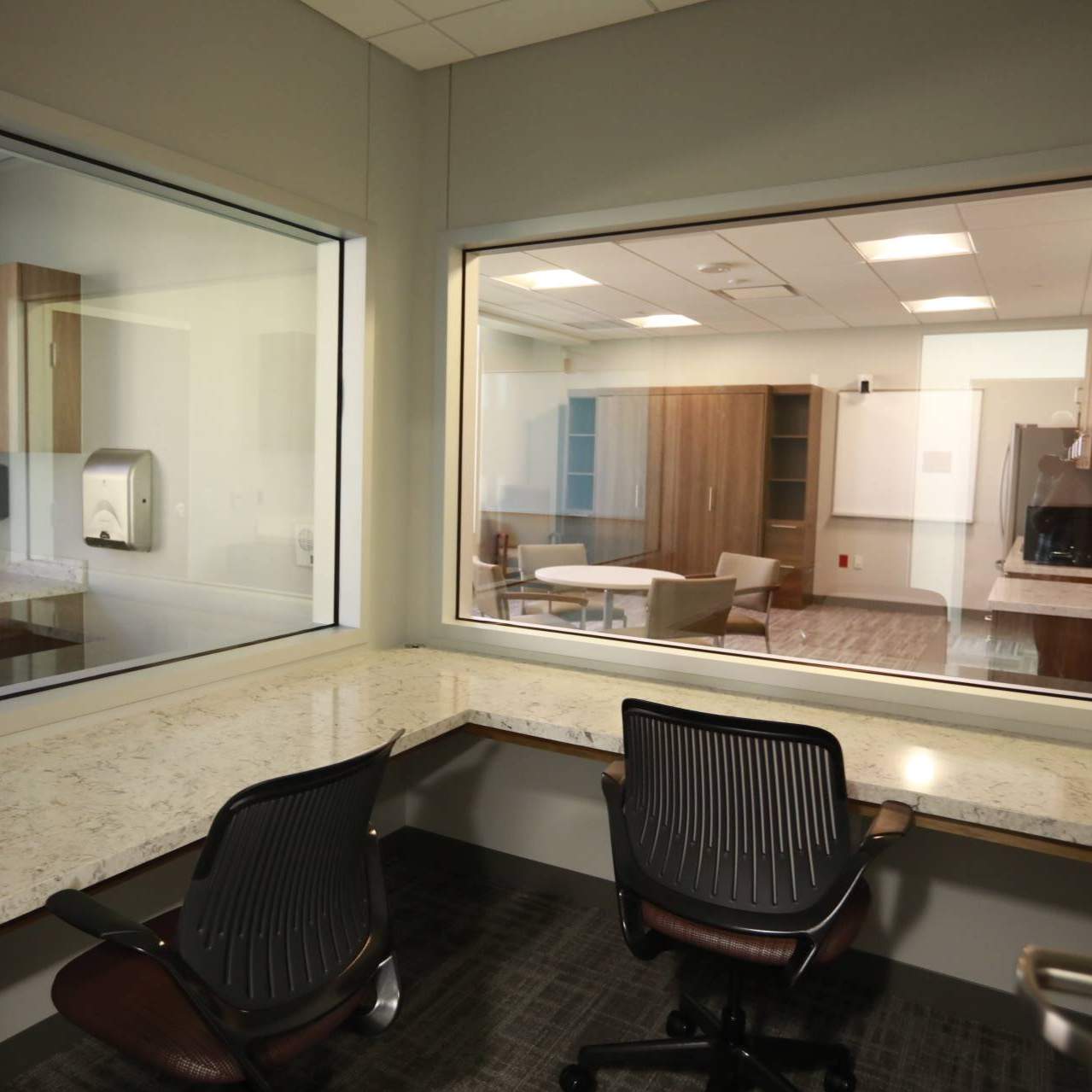 a viewing room overlooks two other mock patient meeting rooms where students can be observed for a grade