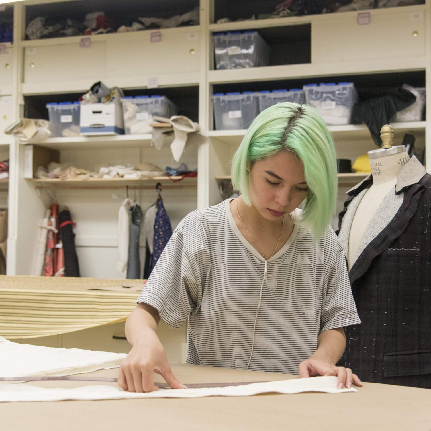 A student measures fabric for a costume.