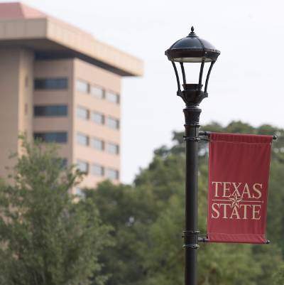 Texas State banner hanging from light pole with JCK in background