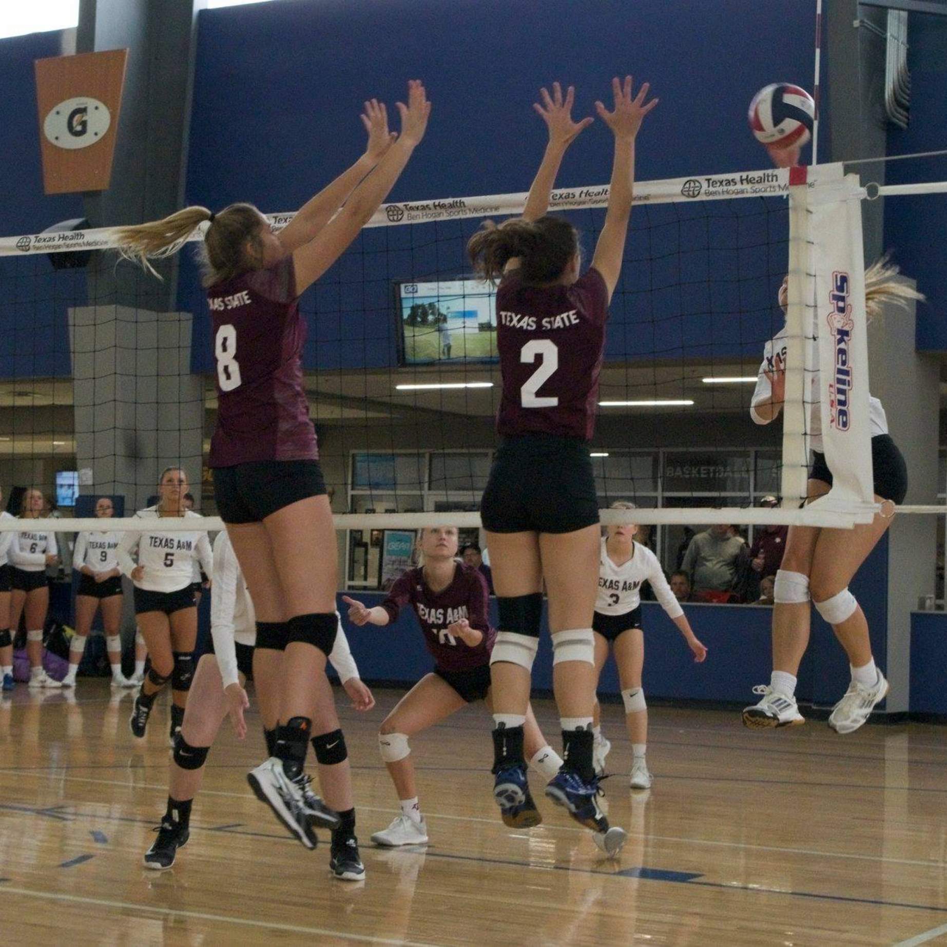 Women's Volleyball players attempt a block