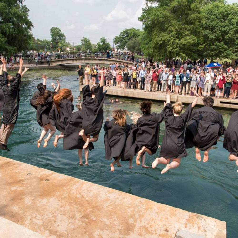 large group of graduates jump into the river