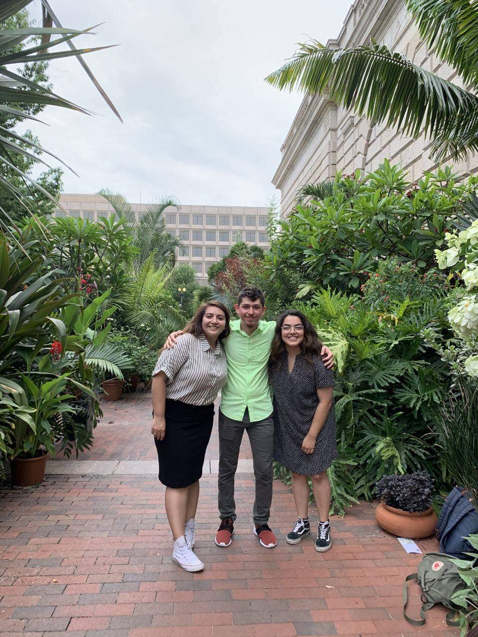three students smiling and posing in a botanical garden