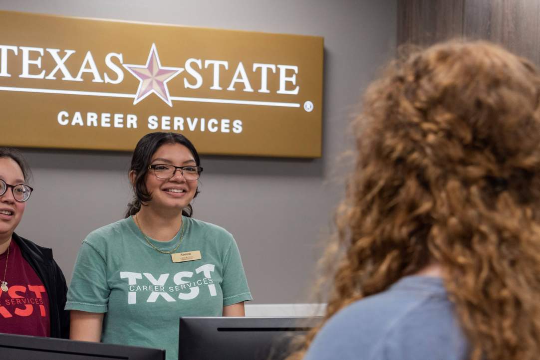 A student worker smiles at an incoming student in the career services office