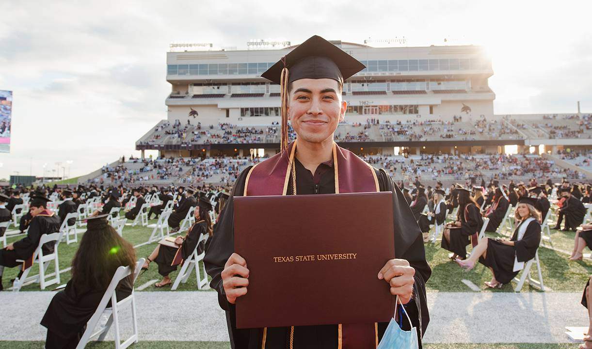 young man holding diploma and smiling