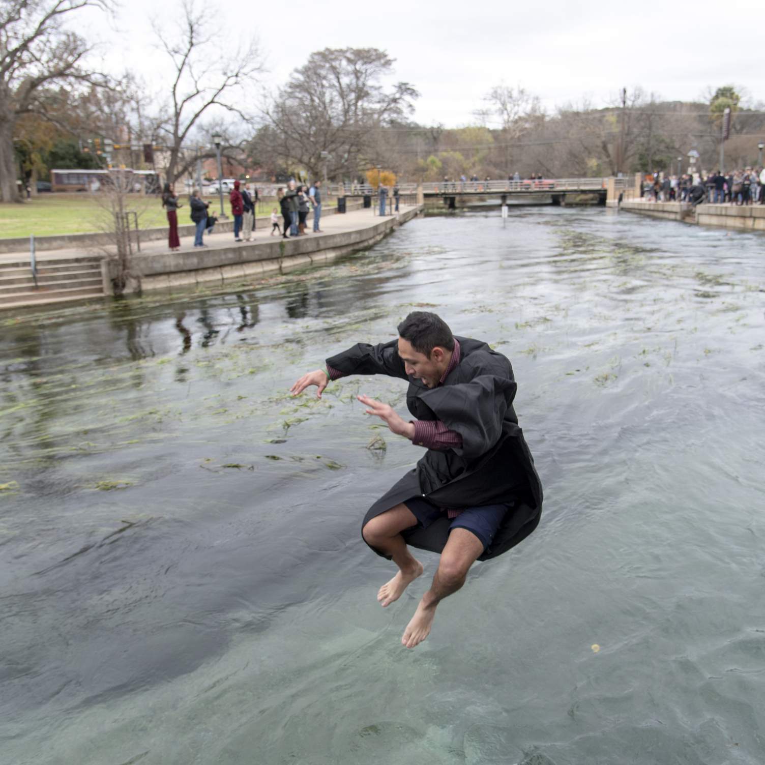 graduate jumping into San Marcos river in Sewell Park