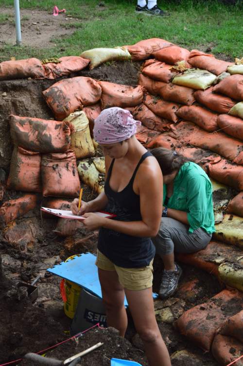 Archaeologists taking notes in excavation pit