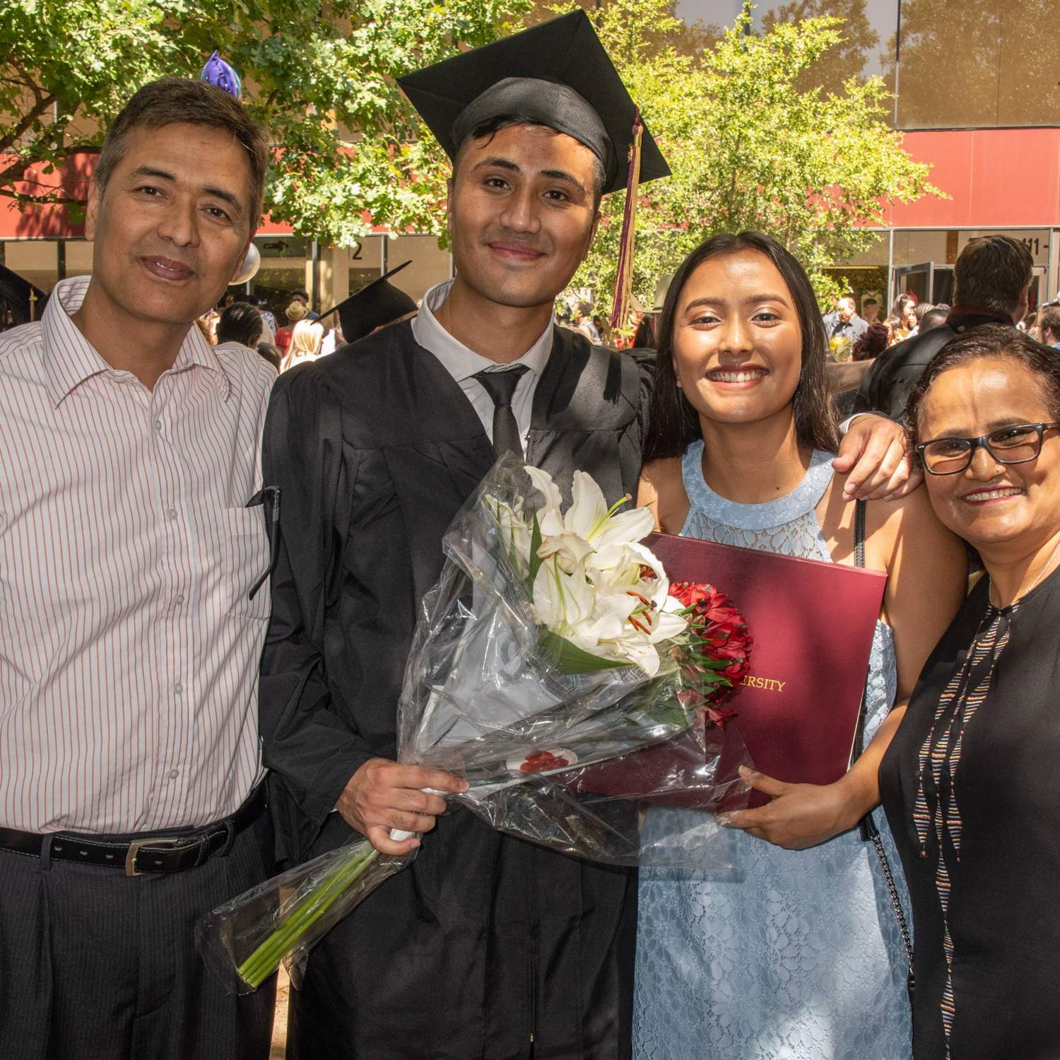a graduate with his family and diploma 