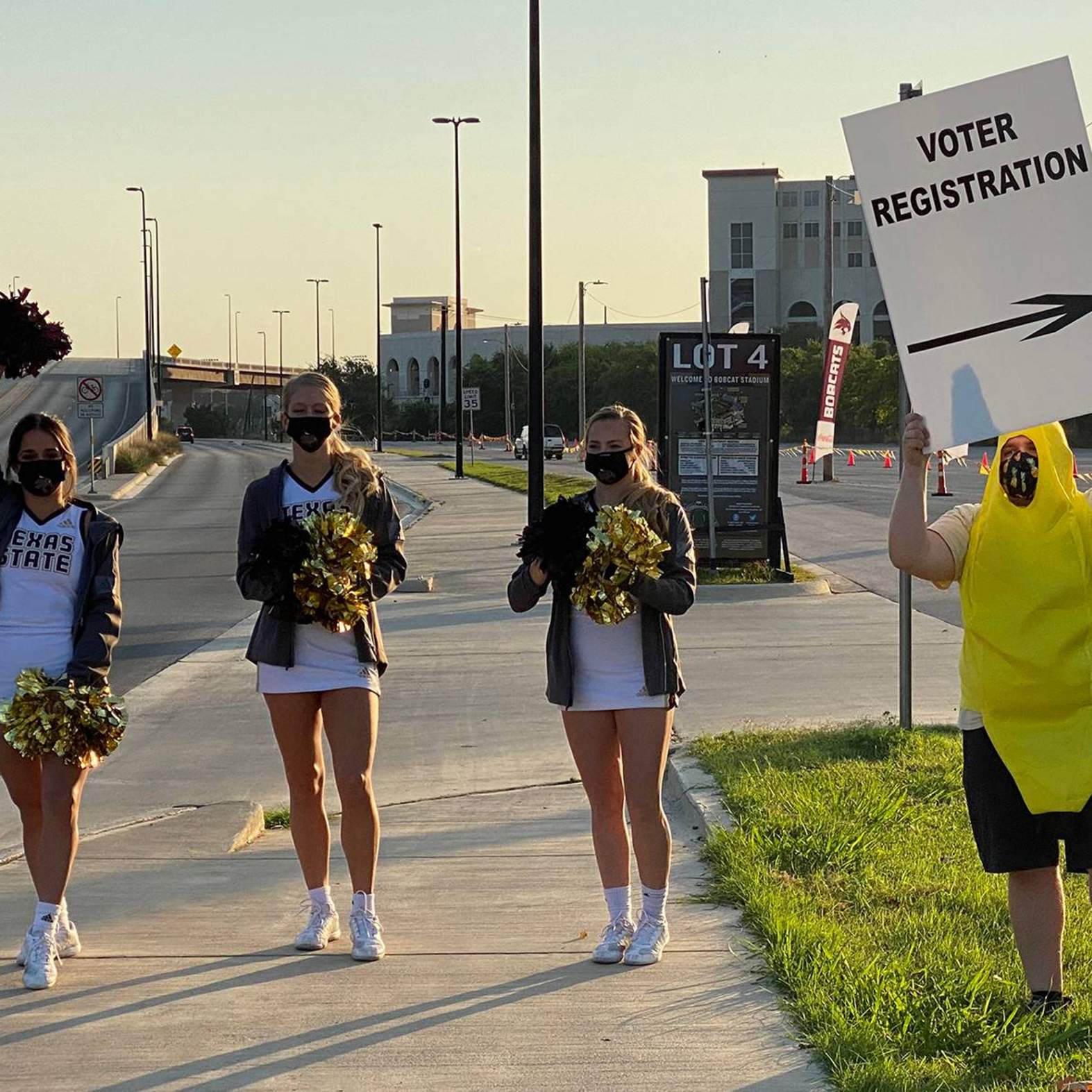 cheerleaders holding signs encouraging people to register to vote