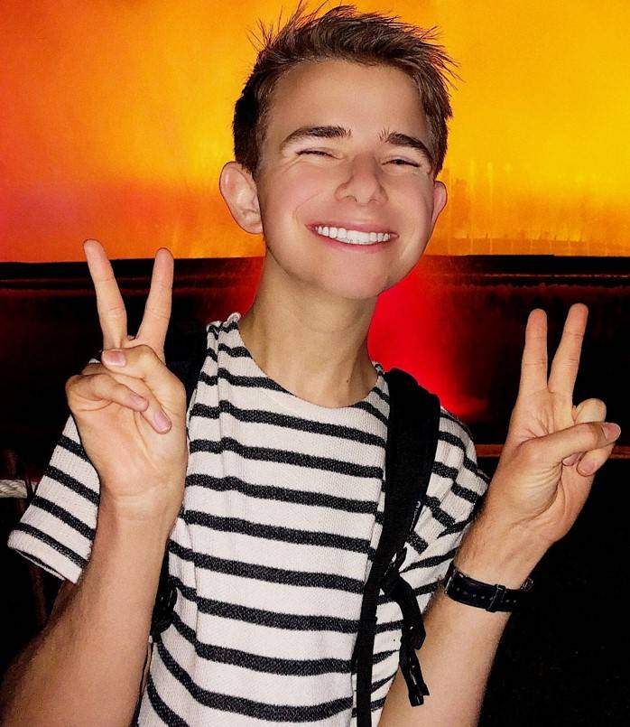 Logan Taylor holding up peace signs with bright orange lighted background
