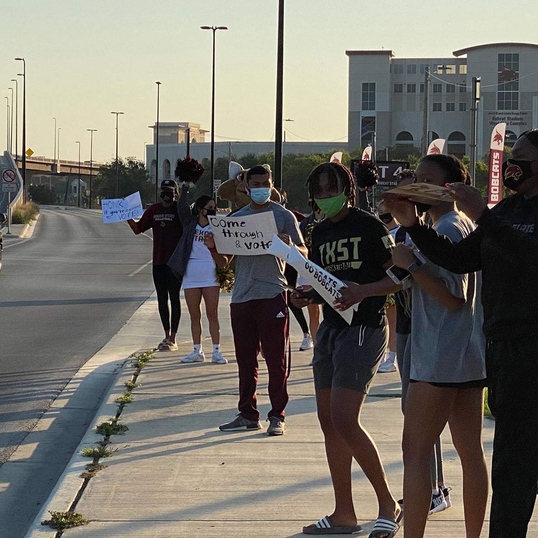 students on side of road holding signs