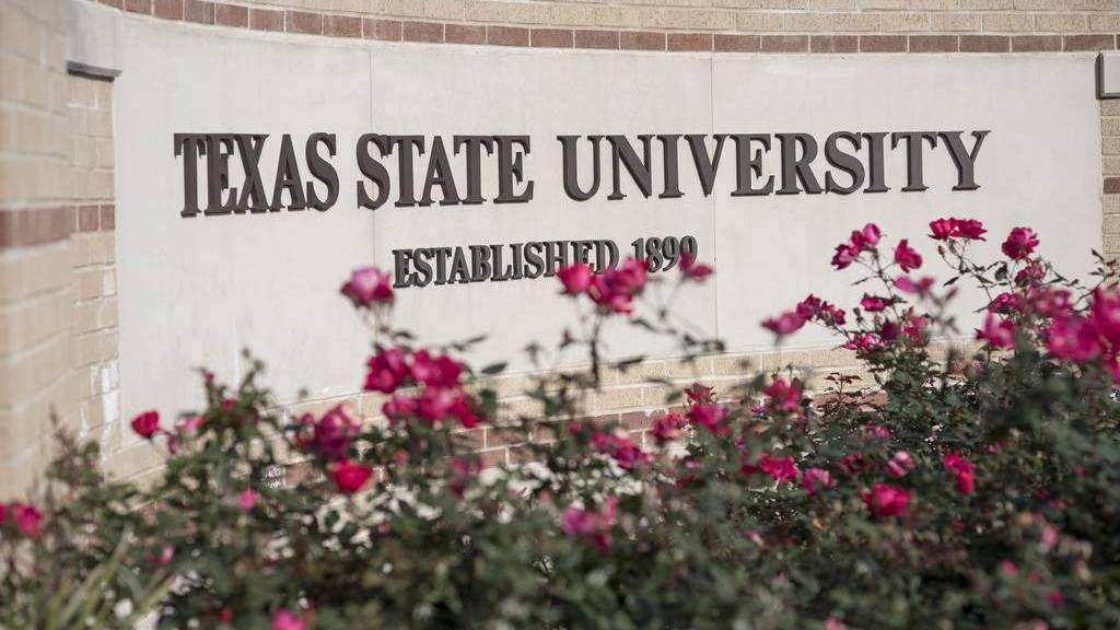 Texas State University stone sign with flowers and landscaping