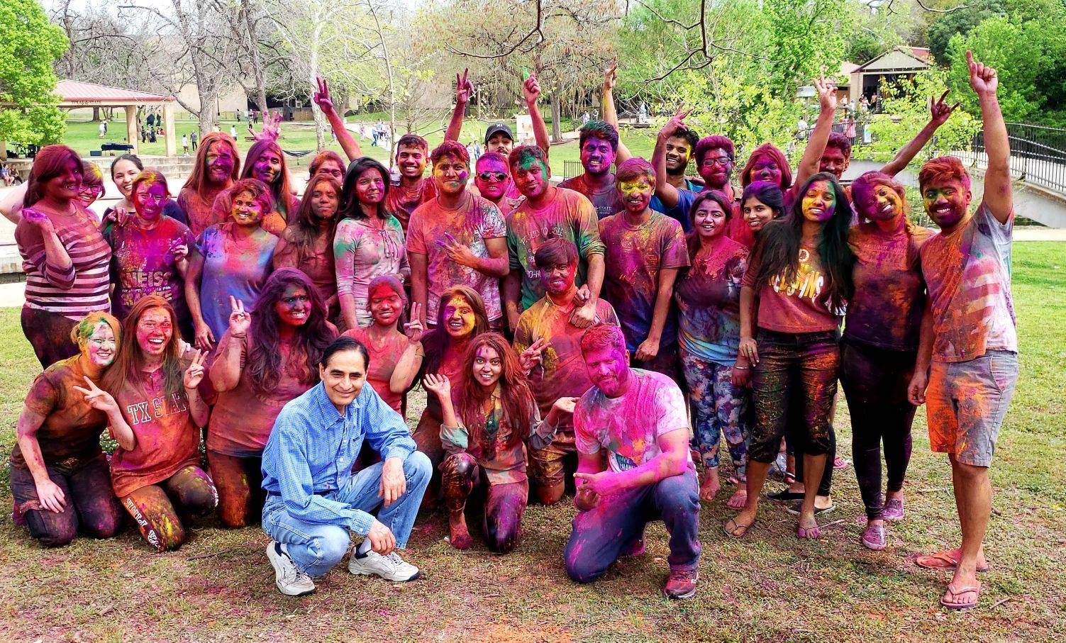 A group of students covered in colored powder smile for a photo at Sewell Park