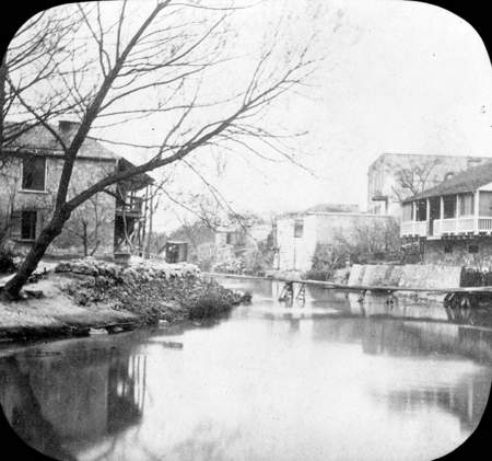Historic black and white photograph showing the San Antonio river and John Twohig's home on the left back of river