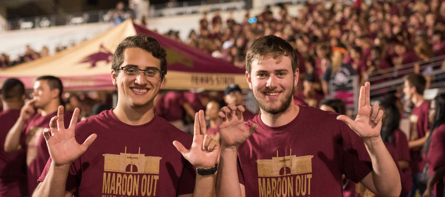 graduated student makes heart of texas hand sign