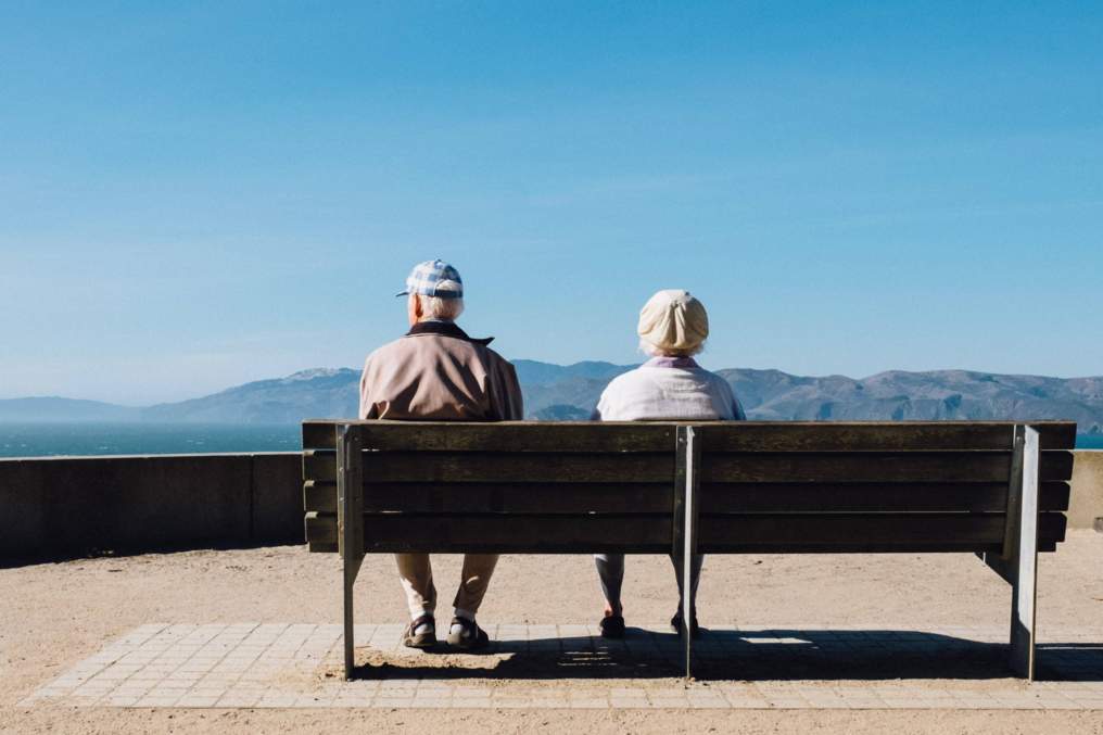 elderly couple on a bench overlooking mountains