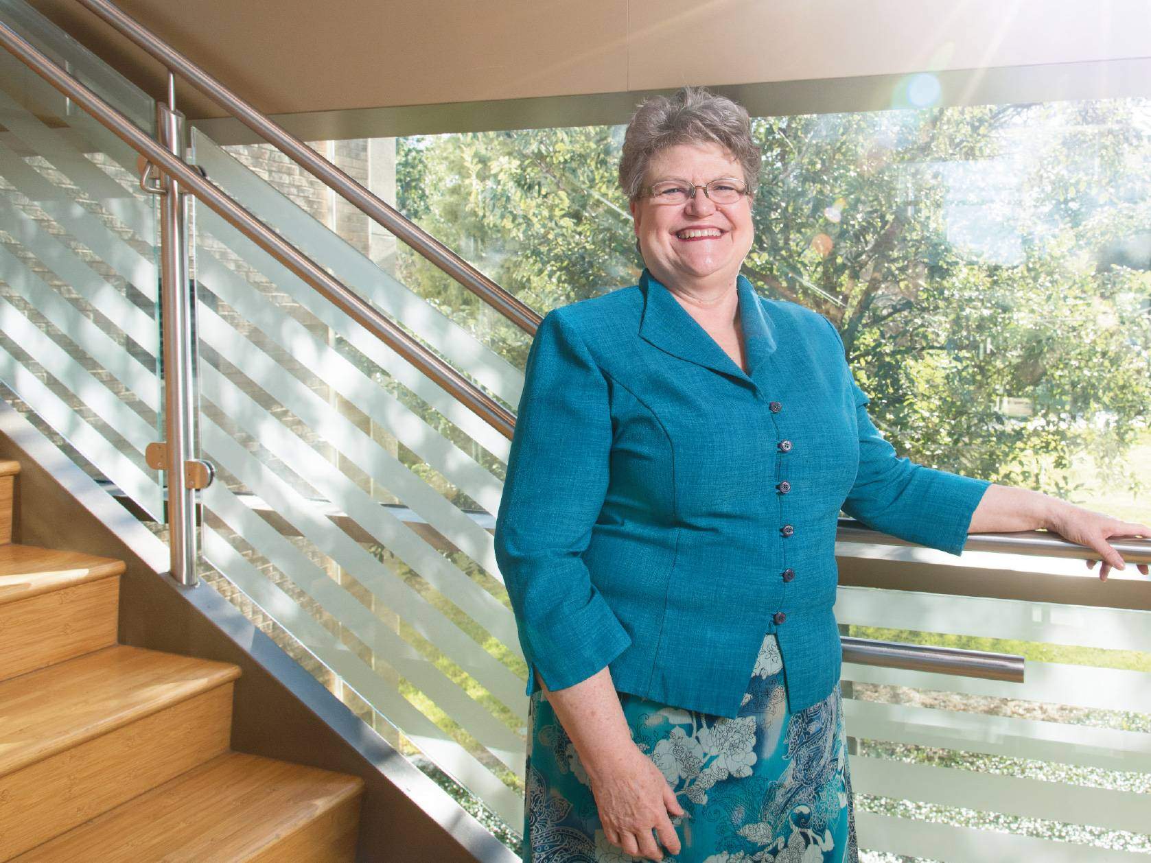 Dr. Sandra Duke stands in a sunny staircase, smiling