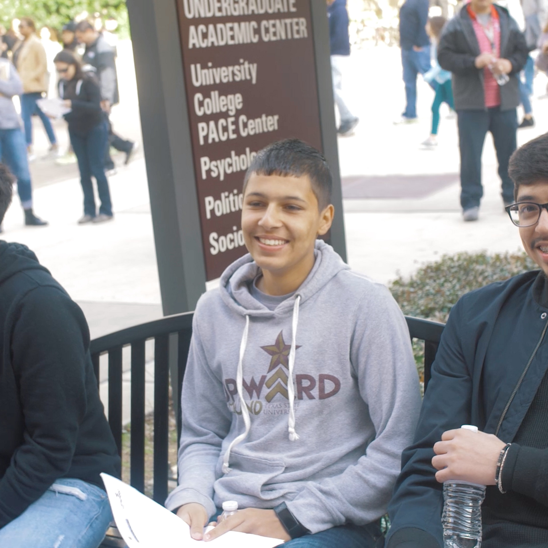 Three Upward Bound participants sitting on a bench on Texas State campus
