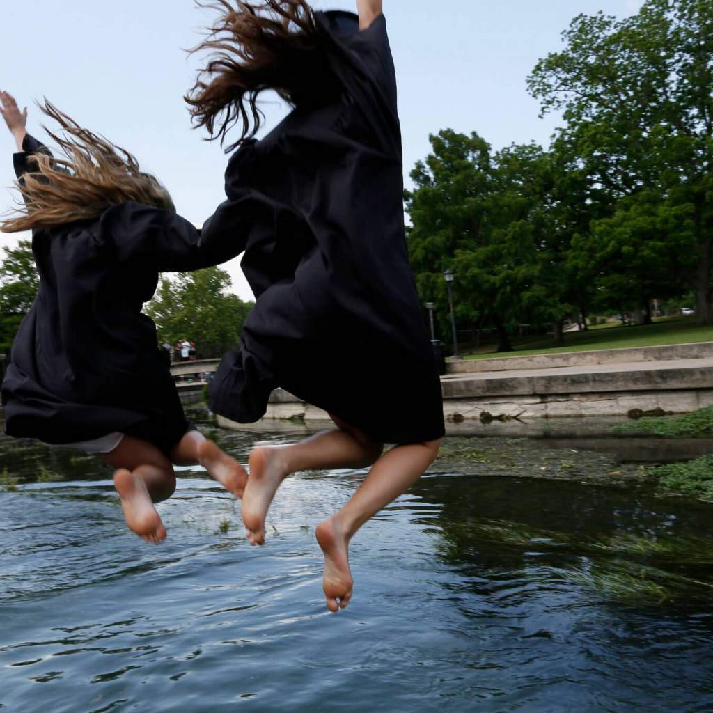 Graduates jump into the San Marcos River.