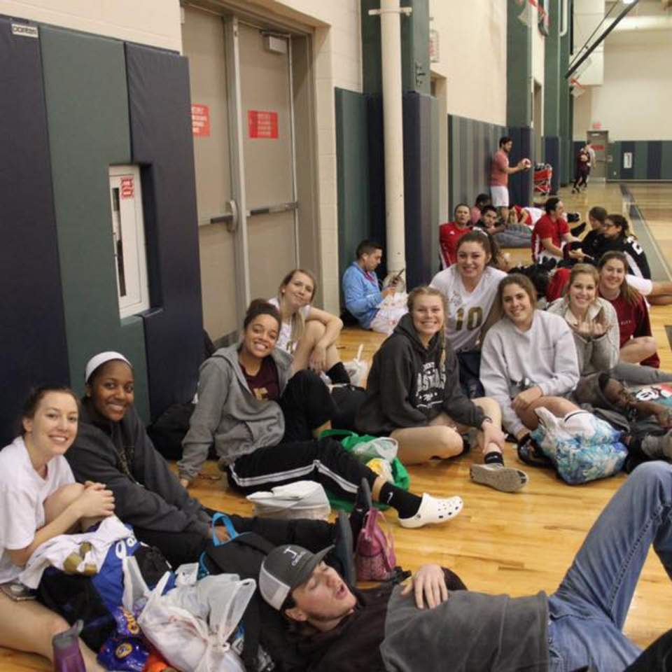 Women's Volleyball team lounging on a court between matches