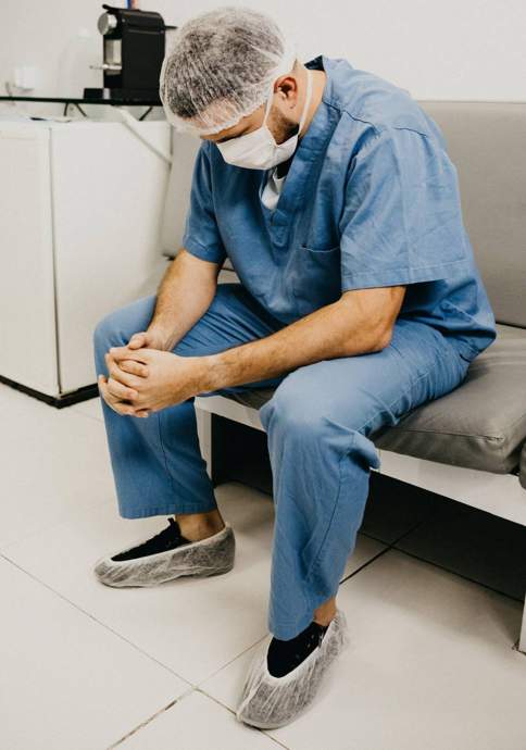 nurse in scrubs sitting with head down