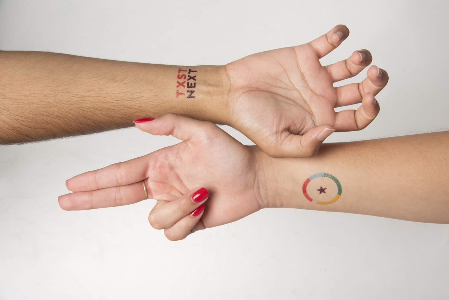 Two hands doing Texas State hand signs have Next temporary tattoos on the inside of their wrists