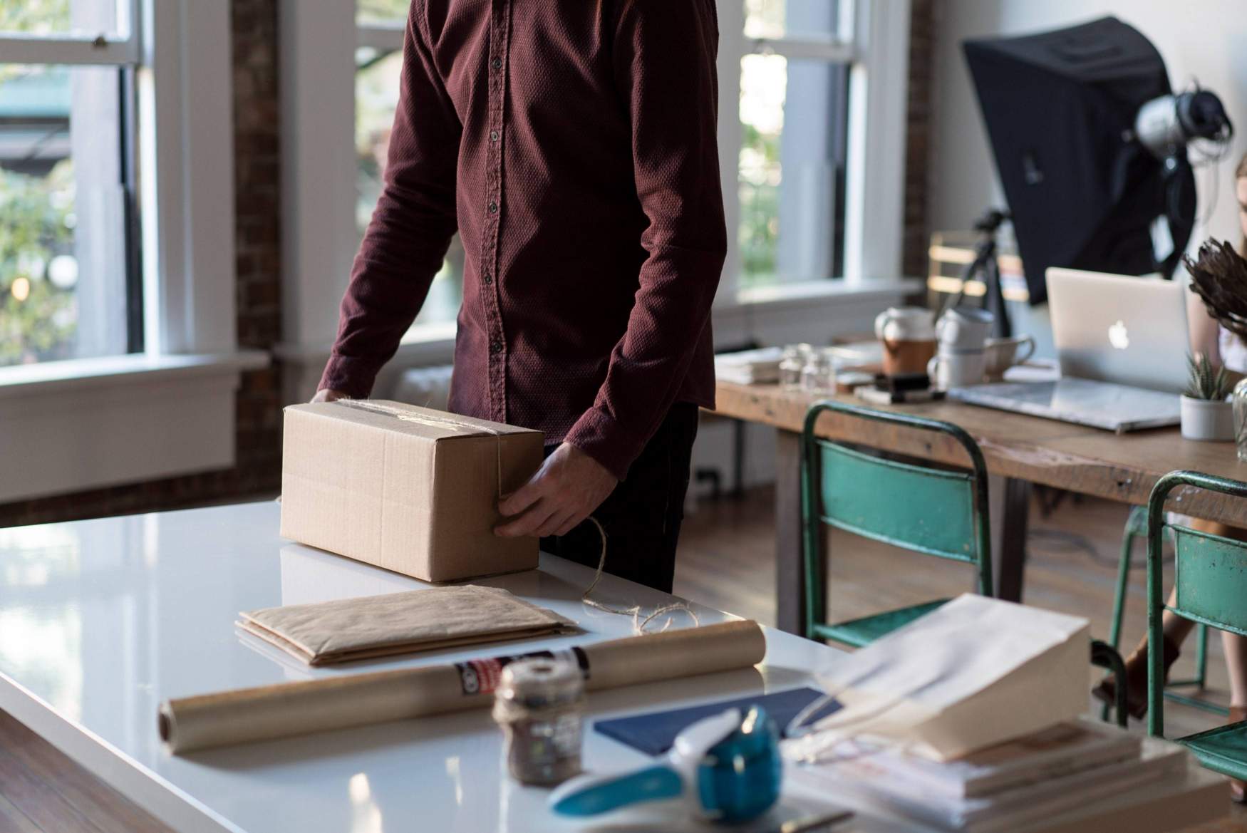 man in maroon shirt, packing box on office table