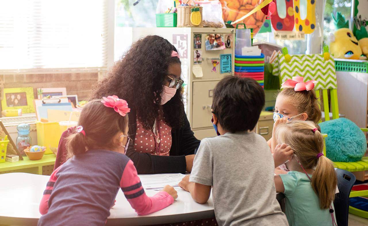 female teacher working with 4 young children