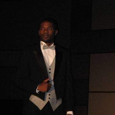 Male student/model wearing a tux walking down the runway at the fashion show.