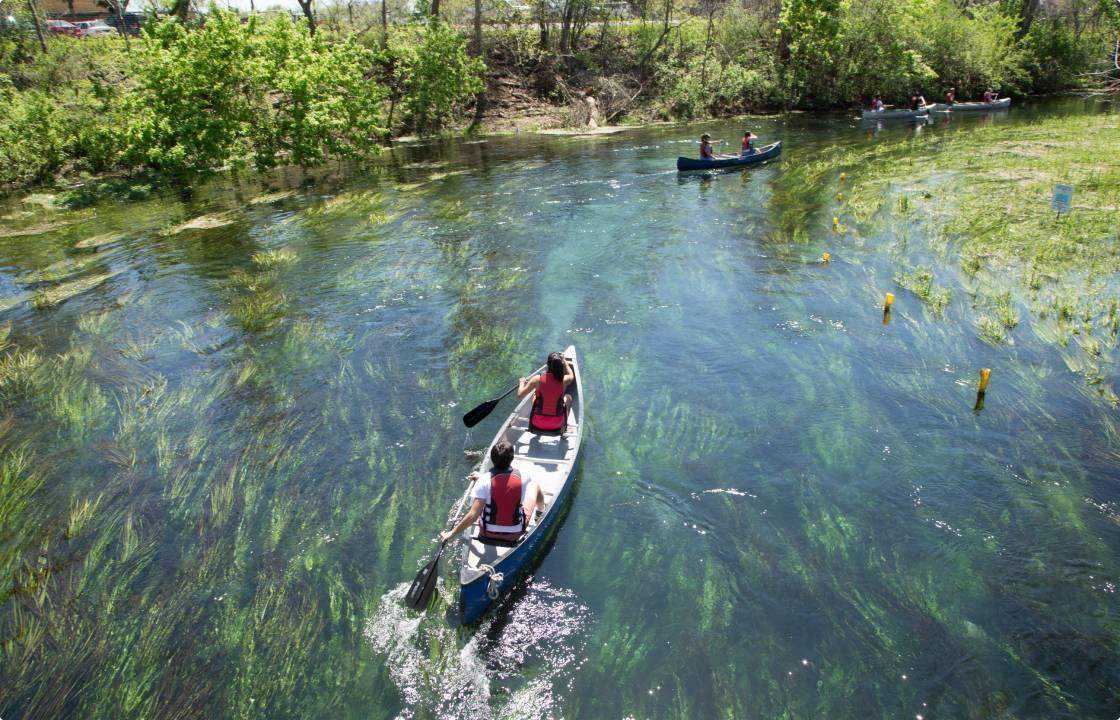 Students paddle a canoe across the river’s clear water