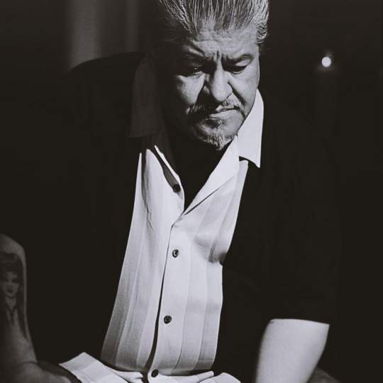 High contrast black and white image of Luis Rodriguez from the waist up.
