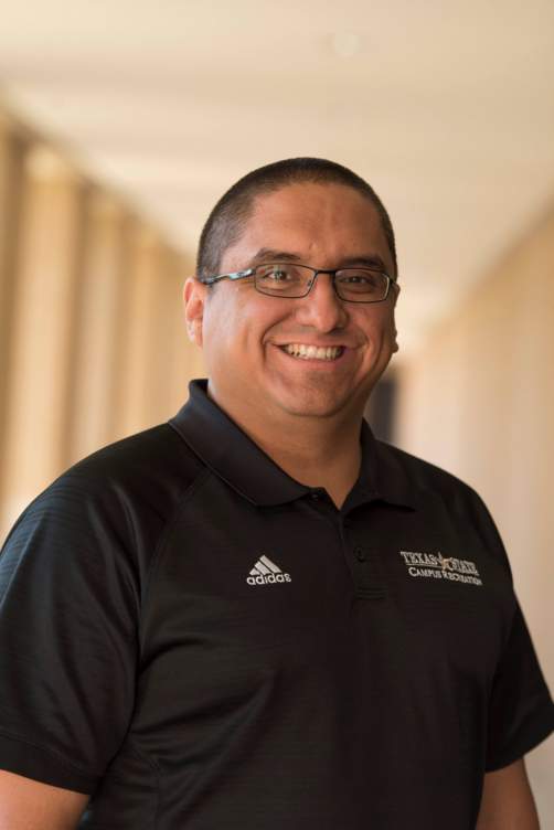 Mario Rios smiling with black glasses and a polo.