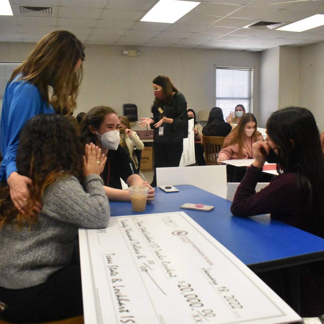 group of student teachers sitting with large checks