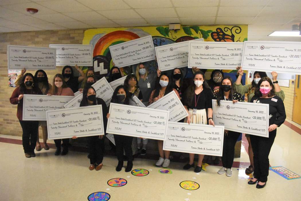 group of student teachers holding large checks