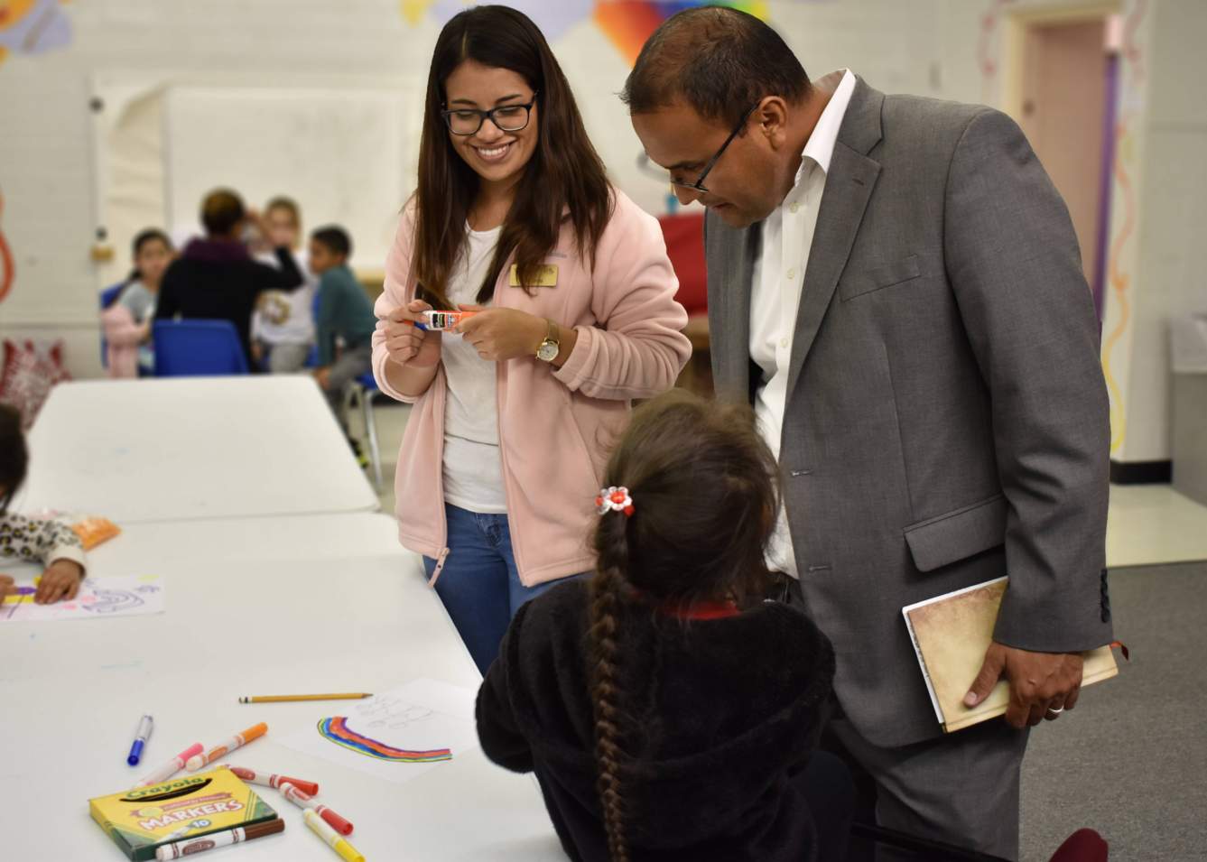 Texas State student Anahí Ortiz and SMCISD Bilingual Education Director Benjamin Grijalva discuss a child's literacy activity with her.