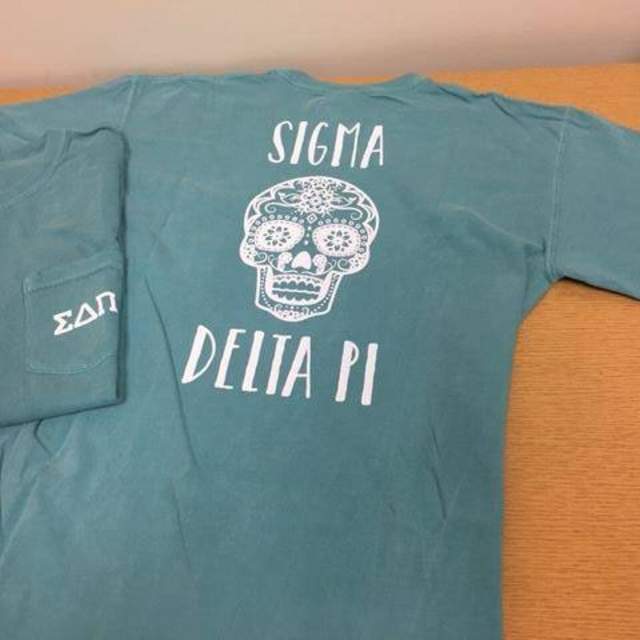 Photo of two Sigma Delta Pi t-shirts, one folded, one lying flat