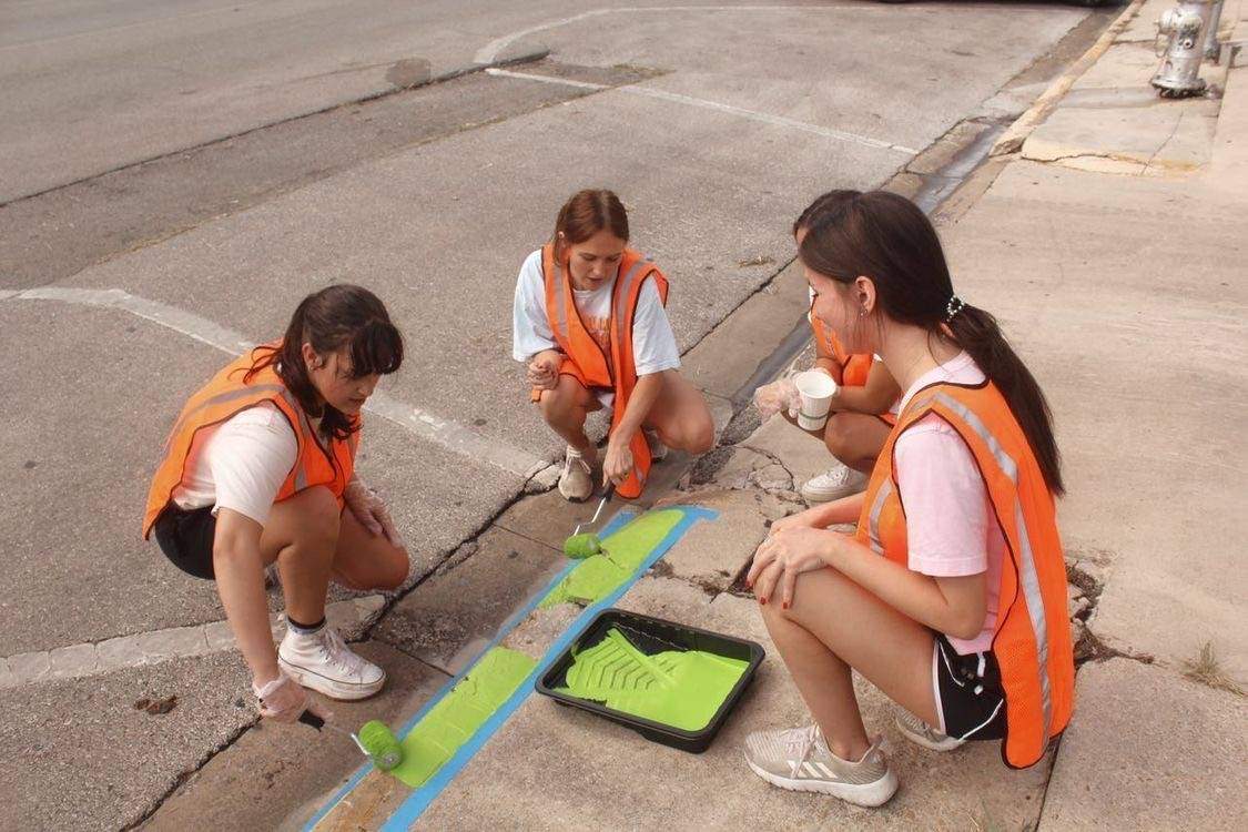 three women painting sidewalks