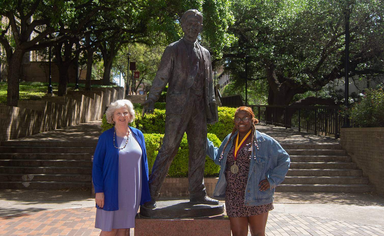 two women standing next to statue of LBJ