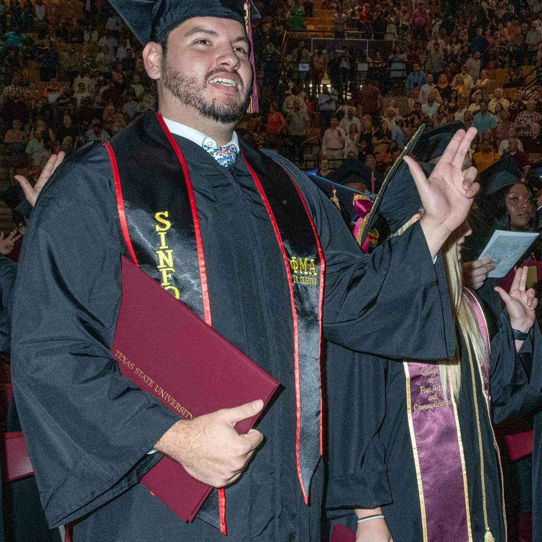 Graduate doing Texas State Hand Sign