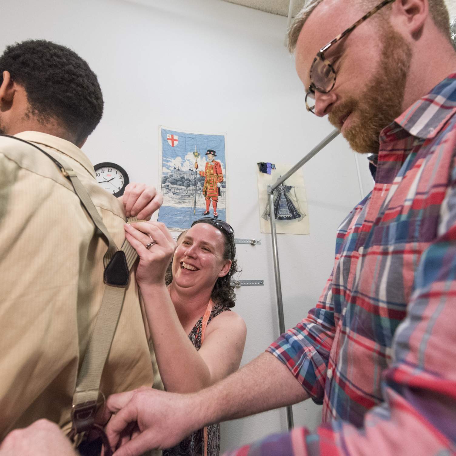 Professor adjusts suspenders on actor during a costume fitting