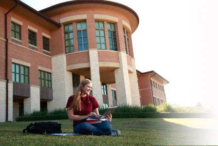 A student sittingon the grass in front of the Avery Building