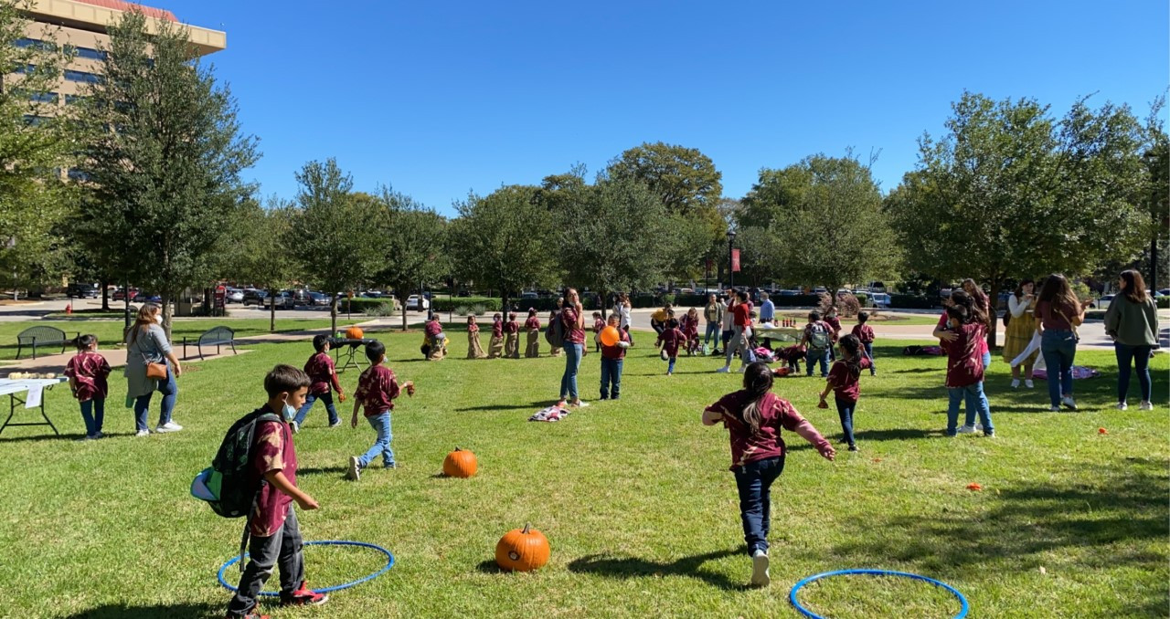 kids playing with hoops and pumpkins on a green lawn