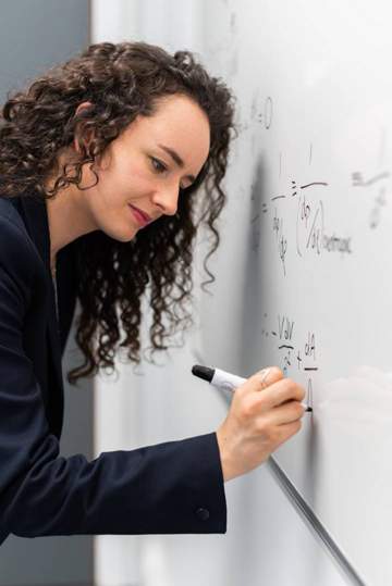woman writing math equation on whiteboard