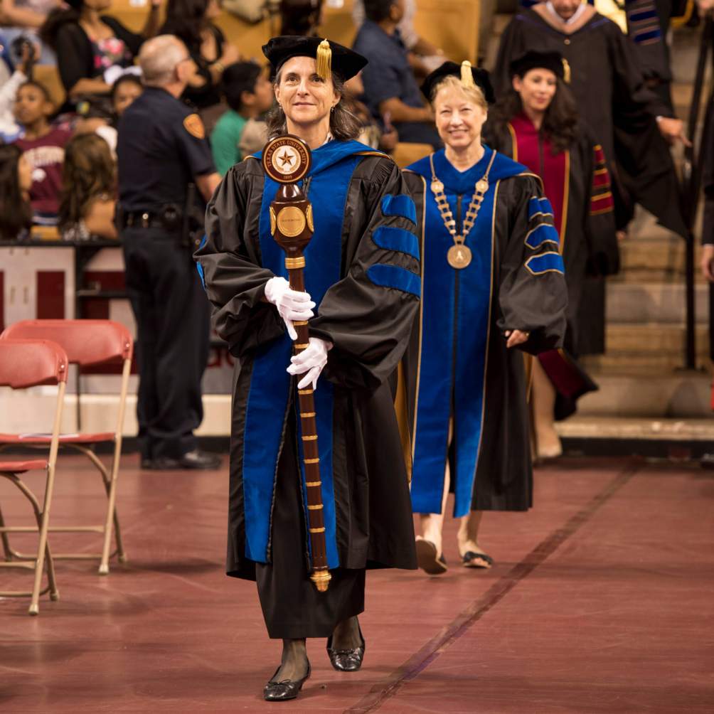 The mace bearer carries the mace that bears the presidential seal of Texas State University, followed by President Denise M Trauth as the processional begins at a Summer 2016 commencement ceremony.