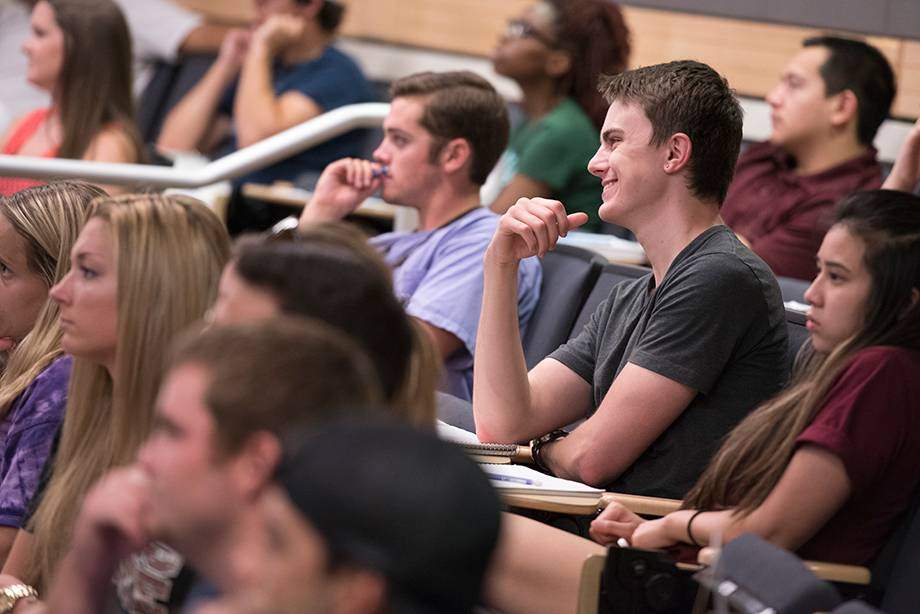 A group of students sit attentively in lecture hall 