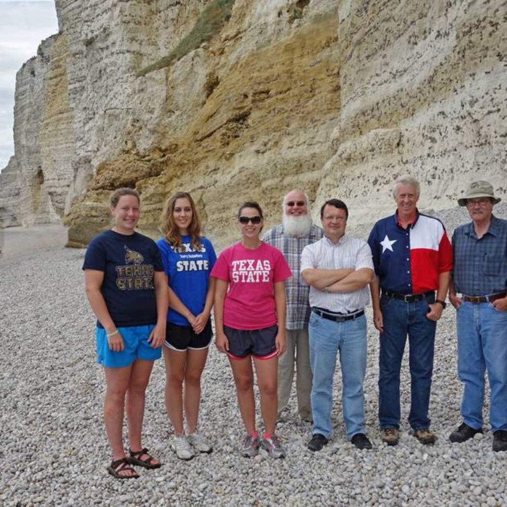 Left to right: Ava Pope, Laura Bright, Hannah Reynolds, Russell Doescher, Jean Langlois, Donald Olson, Roger Sinnott, and Marilynn Olson stand on the Amont beach near Monet’s location for the sunset and daytime paintings. The forward point of the Amont promontory and the small Porte d’Amont arch are visible in the distance, about 425 yards away.