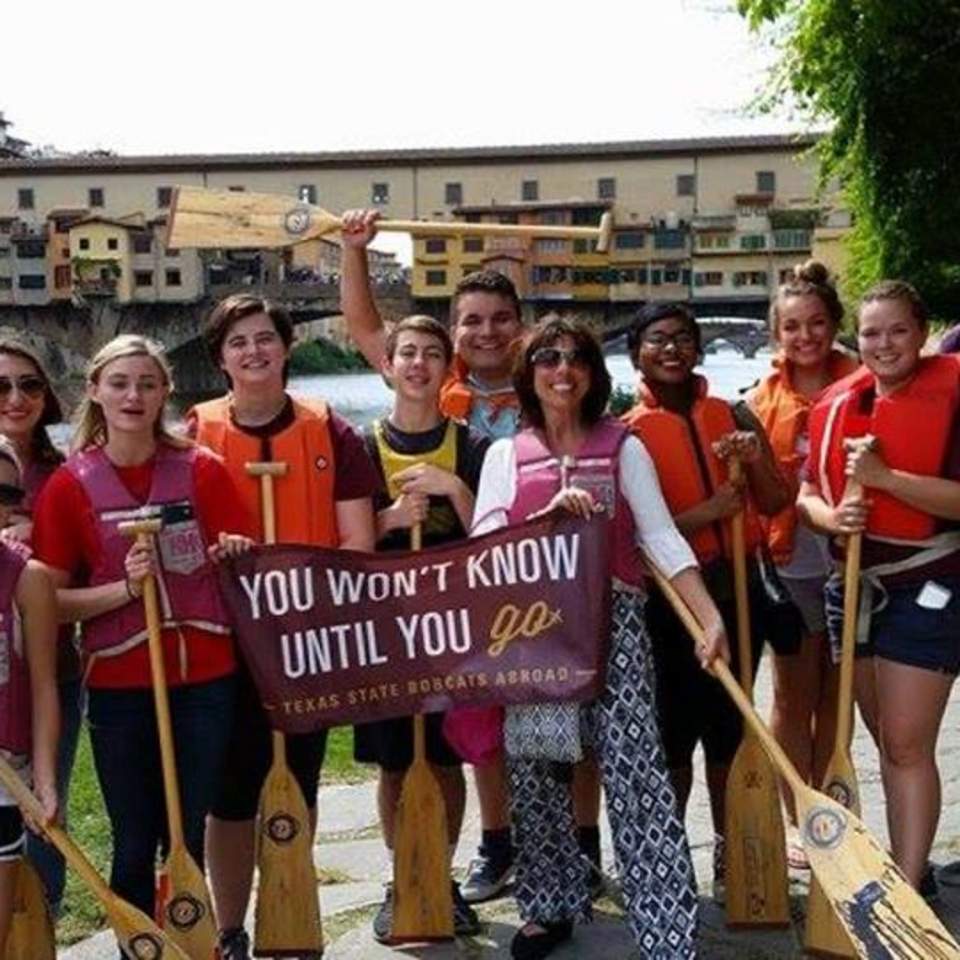 Texas State students and Dr. Di Mauro-Jackson on the shore with paddles