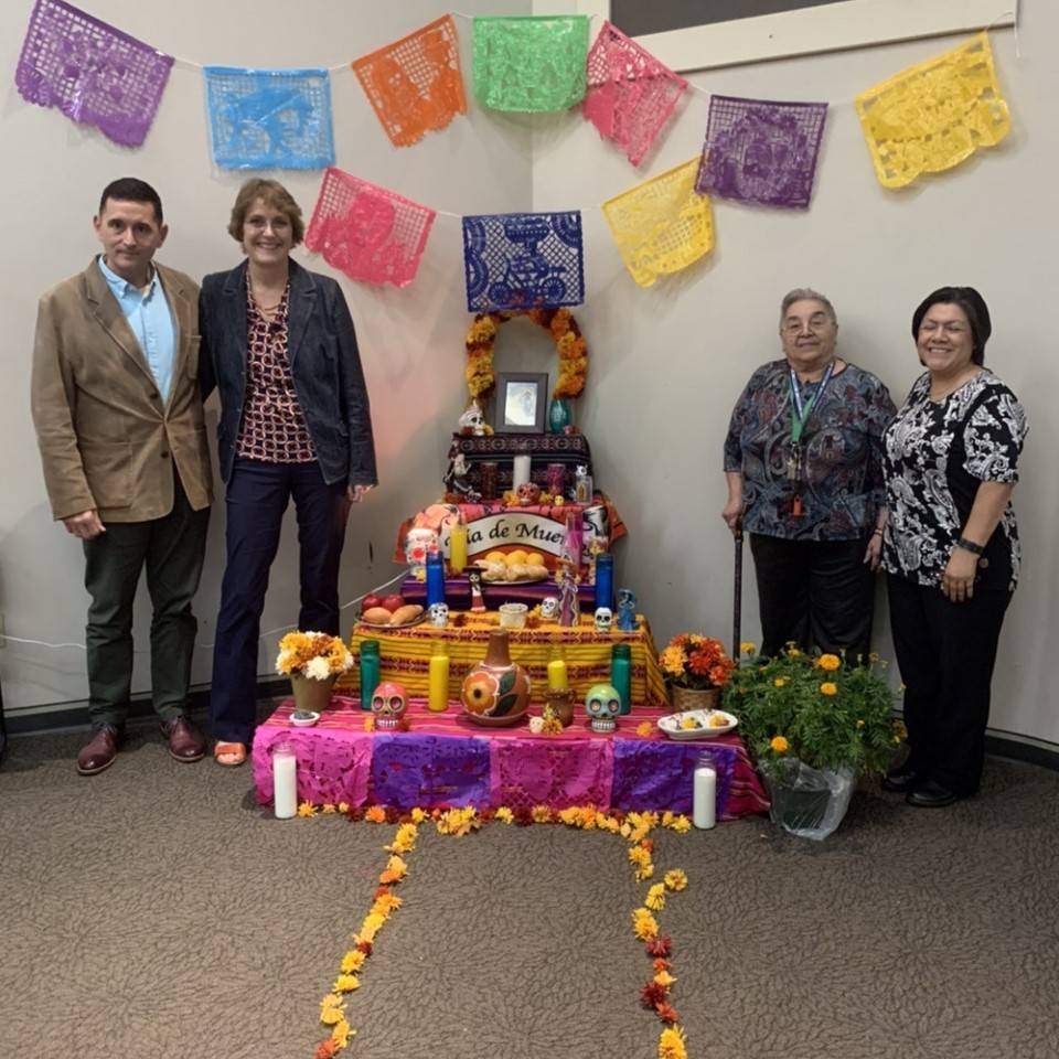 Four people standing around a Day of the Dead altar