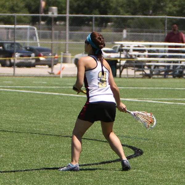 Student standing on field with lacrosse stick in hand