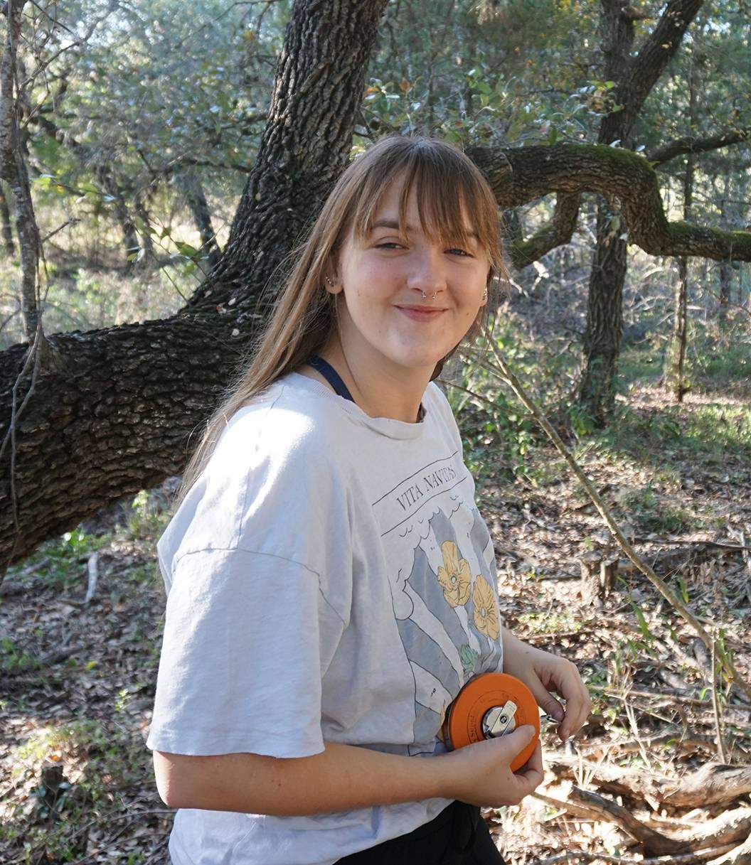 young female student standing in wooded area