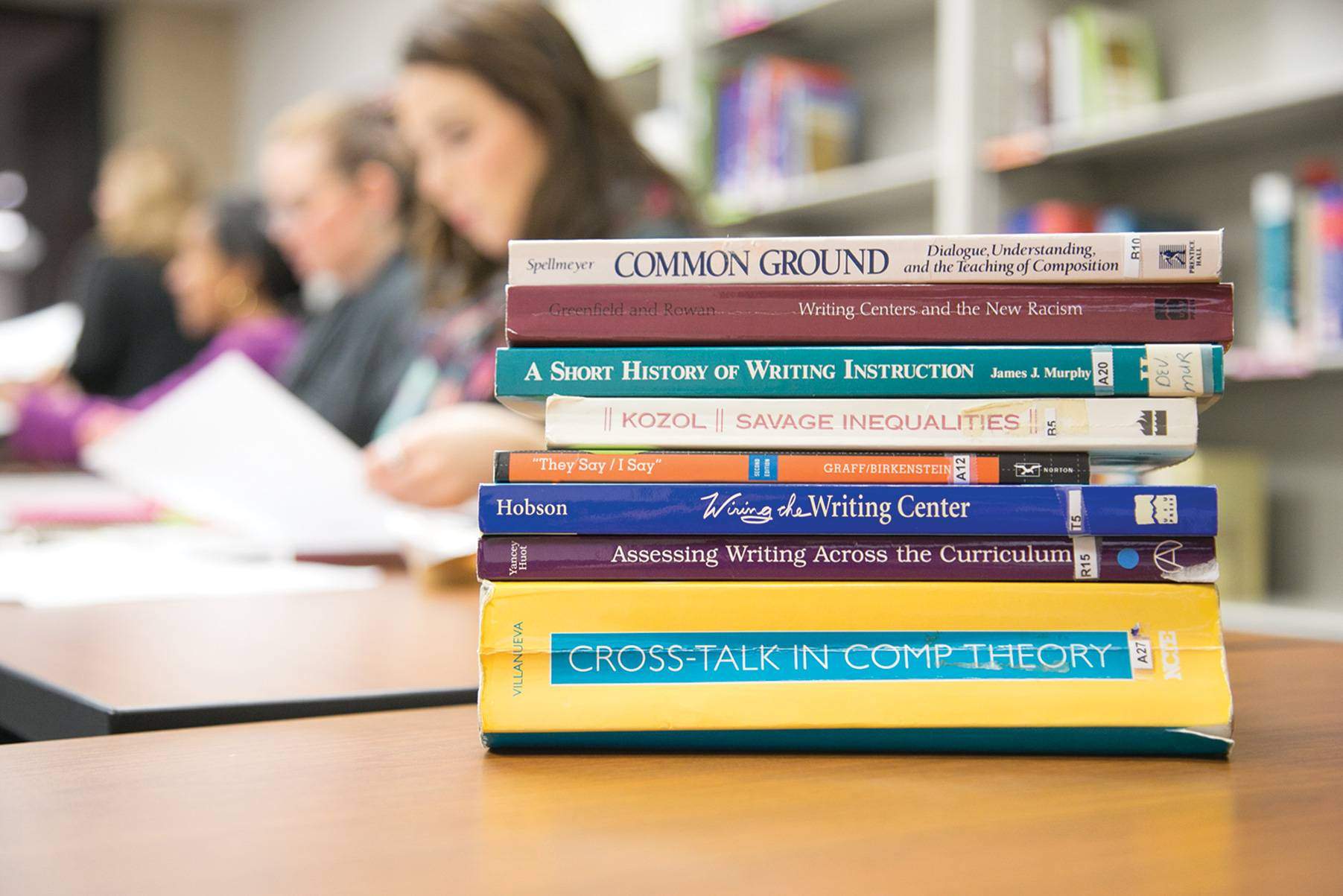 Books set on a table with students in the background. 